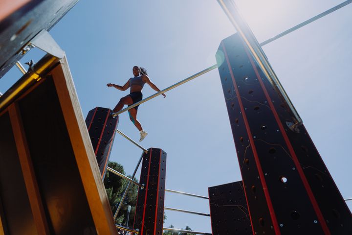 En person utövar parkour på en hinderbana under en klar himmel.