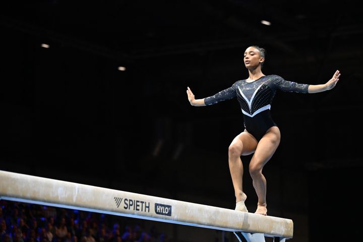 En gymnast utför en balansövning på bom.