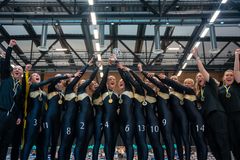 Grupp av glada gymnaster i svarta dräkter firar med en pokal och medaljer.