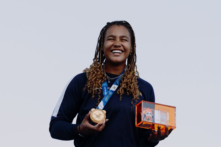 Parkourmästaren Miranda ler med guldmedaljen runt halsen.