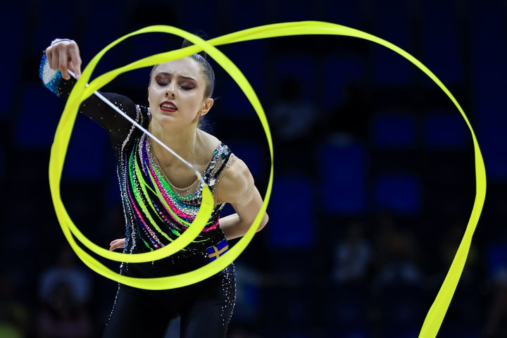 En gymnast utför ett bandprogram i en tävling.