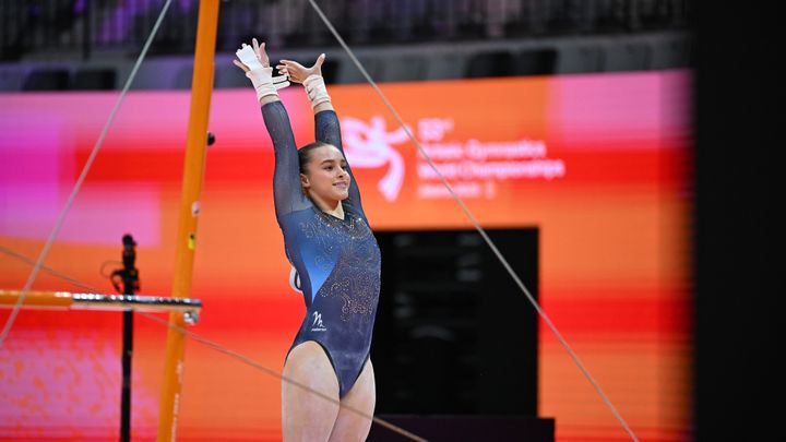 Kvinna i gymnastikdräkt jublar framför barr-redskap vid VM i Jakarta.