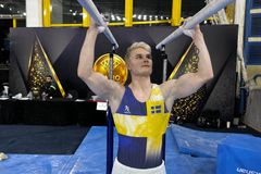 Gymnast i Sverigekläder står vid herrbarren.