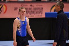 Glad gymnast i landslagsdräkt går mot sin tränare.