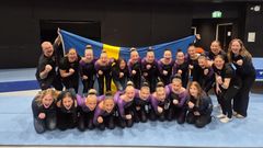 Ett lag firar seger framför en svensk flagga inomhus.