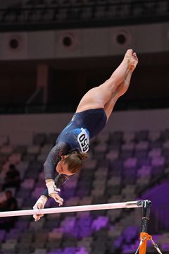 Bild på en gymnast som utför en övning i barren under en tävling.