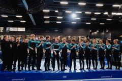 En grupp gymnaster i uniform står på en matta inomhus och klappar.