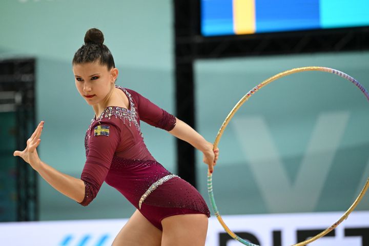 Kvinna i gymnastikdräkt håller i ett tunnband under en tävling.