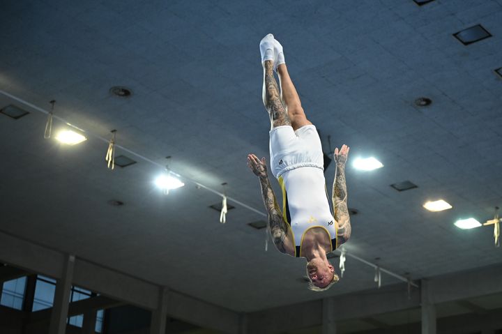 Man som utför ett gymnastikhopp under en tävling i en sporthall.