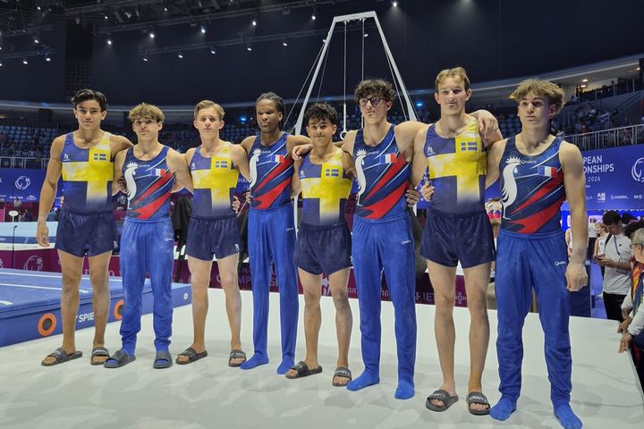 Bild på det svenska juniorlaget och laget från Frankrike i gymnastikställningar vid en tävling.