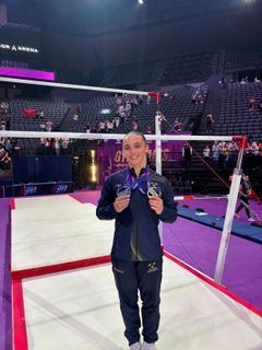 Emelie visar upp sina två medaljer i gymnastikhallen.