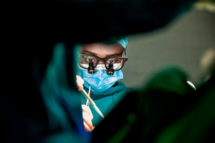 Kirurgklädd person med luppglasögon står vid operationsbord. Närbild utan övriga detaljer.