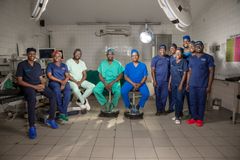 Elva läkarklädda personer i en operationssal. De ler mot kameran.