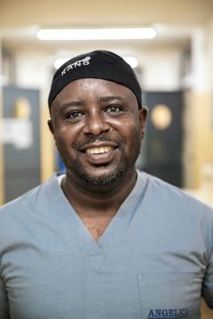 Läkarklädd man ler mot kameran.