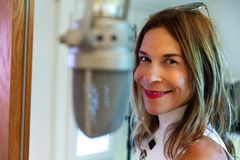 Närbild/porträtt av kvinna med brunt axellångt hår som ler mot kameran. Längst fram, nära kameralinsen, är en stor sångmikrofon.