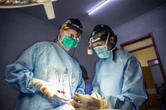 Två personer i operationskläder står vid ett operationsbord och ser ut att vara mitt i en operation.