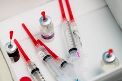 Närbild av antibiotika i flytande form på flaska, samt sprutor, på ett bord.