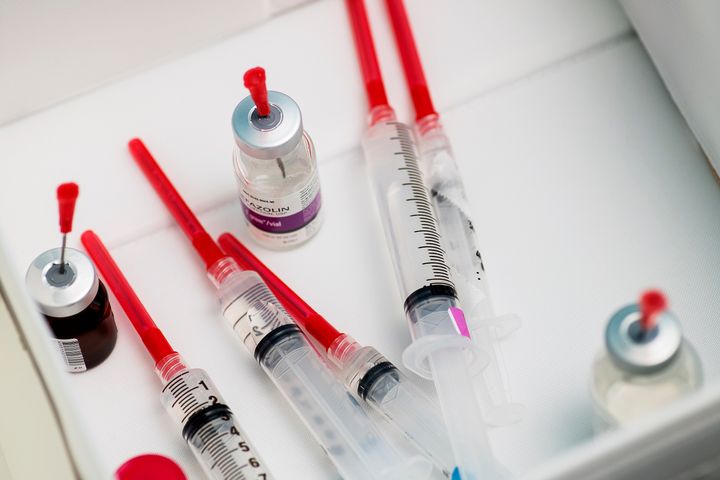 Närbild av antibiotika i flytande form på flaska, samt sprutor, på ett bord.