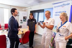 Fyra personer, varav två läkarklädda, står och diskuterar framför en vepa med texten Operation Smile.