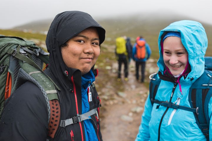 Två personer som fjällvandrar i regn.
