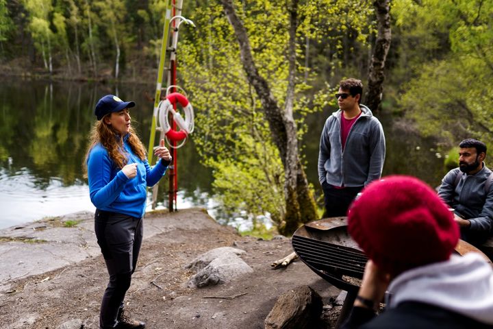 Kvinna som pratar inför en grupp i skogen i samband med en vandring