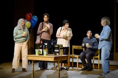 En grupp personer står på en teaterscen och pratar med varandra.