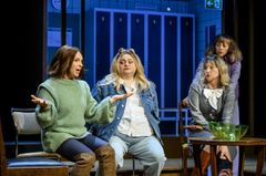 Fyra kvinnor sitter tillsammans på en scen med skåp i bakgrunden.