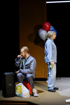 En man och en kvinna står på en scen med ballonger i bakgrunden.