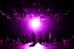 En grupp människor står på en scen upplyst av ett lila ljus.