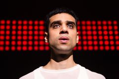 Porträtt av Emil Hedayat på scen med röda prickar på en filmskärm bakom sig.