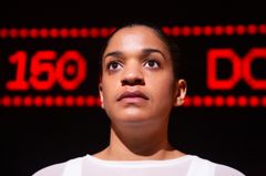 Porträtt av Angelika Prick på scen med röd text bakom sig.