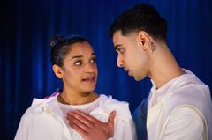 Två skådespelare interagerar på scen i en teaterföreställning.