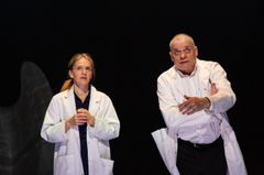 Ann-Sofie Rase och Gerhard Hoberstorfer i vita labbrockar står på en scen och gestikulerar och pratarmed varandra.