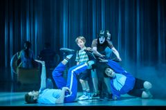 En grupp skådespelare på scenen i färgglada kostymer från föreställningen Pensionat Oskar.