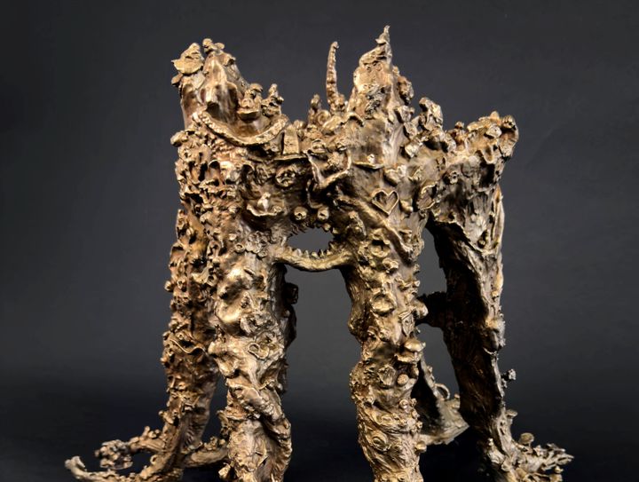 Bronsminiatyr av en komplex, organisk skulptur med många detaljer och texturer.