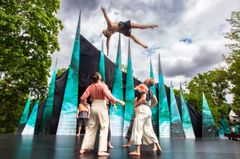 Cirkusartister gör en akrobatisk kastmanöver på en utomhusscen.