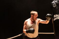 En man med boxhandskar tränar mot en boxningssäck.