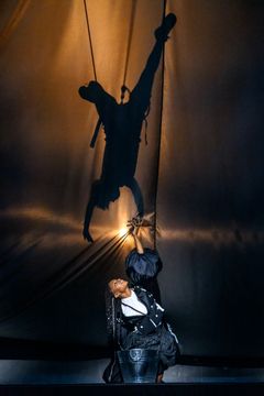 En scen från "Lonely Together" med en skådespelare under en stor skugga av en akrobat på en vägg.