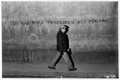 En man går längs en trottoar framför en vägg med texten "Du har bara tristessen att förlora!".