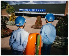 Två barn i blå hjälmar står framför en Domus-butik.