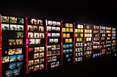 Ett mörkt rum med flera rader av foton uppsatta på en vägg.