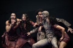 Fem dansare i kostymer utför en intensiv och uttrycksfull dans.