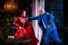 Lena Olin och Peter Andersson i färgglada kostymer agerar intensivt på en teaterscen.