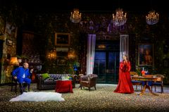 Lena Olin och Peter Andersson på scen med ett rikt dekorerat rum, antika möbler och flera ljuskronor.