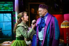 Victoria Dyrstad och Peter Andersson i färgglada kostymer står vända mot varandra. Victoria Dyrstad greppar tag om Peter Anderssons handled.