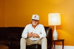 En vitkllädd man sitter mot en gul vägg