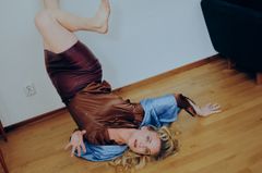 Skådespelerskan Liv Mjönes ligger upp och ner i ett rum med trägolv.