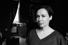 Kvinna i ett mörkt rum, med ljuset från ett fönster i bakgrunden.