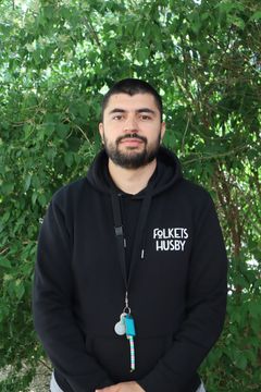 En person med tröja med texten "Folkets Husby". I bakgrunden syns grönska.