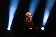 Maria Sid presenterar på Stora scenen med strålkastare i bakgrunden.